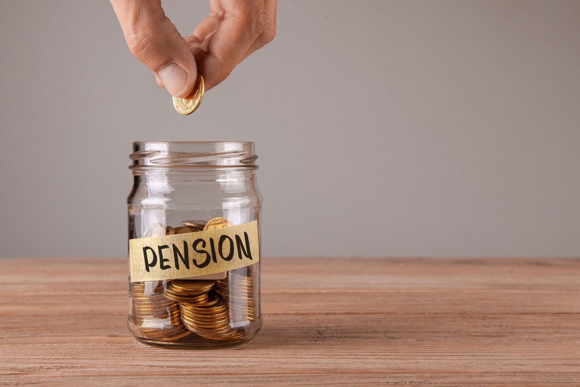 Pension. Glass jar with coins and an inscription pension. Man holds coin in his hand